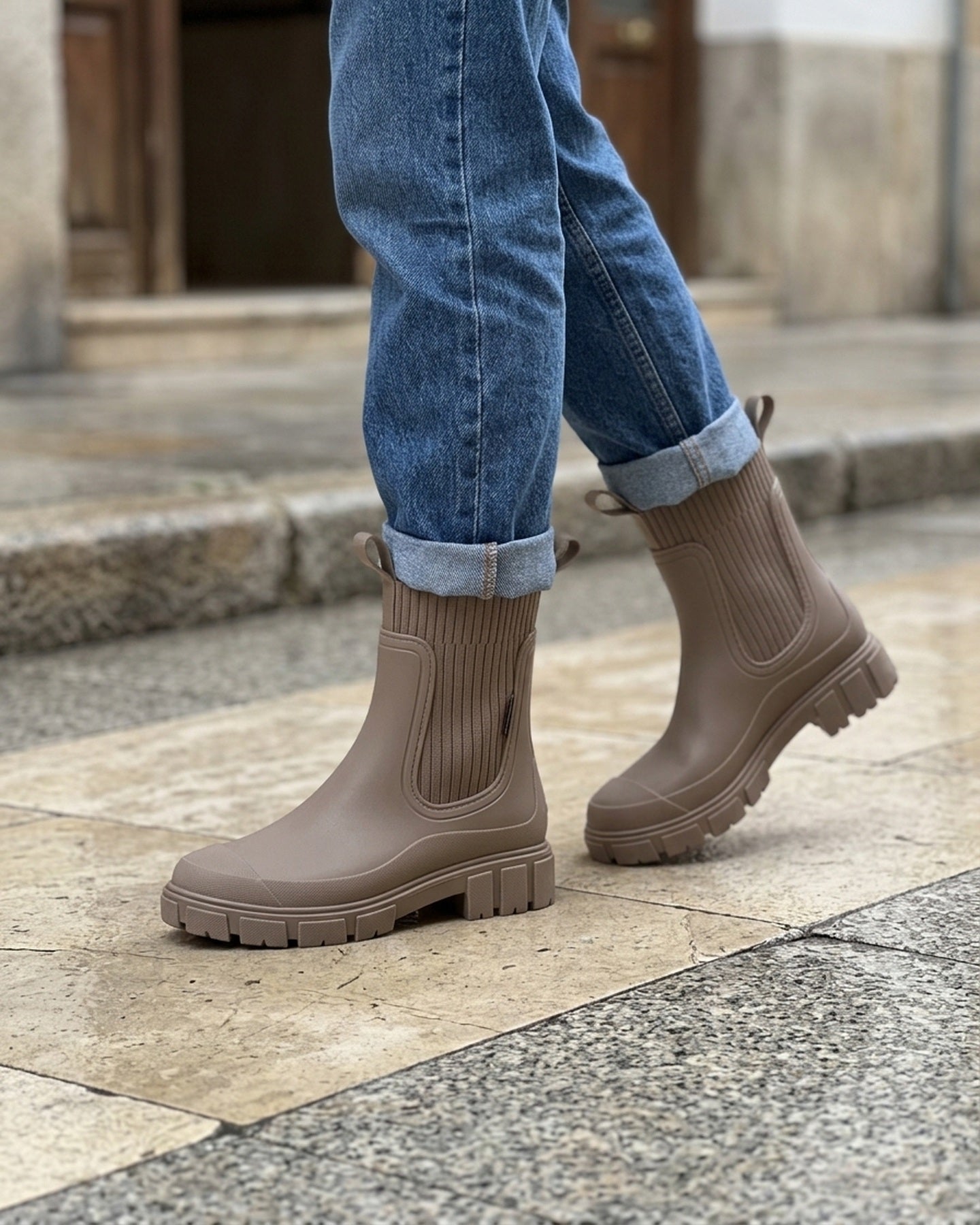 Botas de agua Nerea en marron topo puestas con vaqueros en una calle mojada