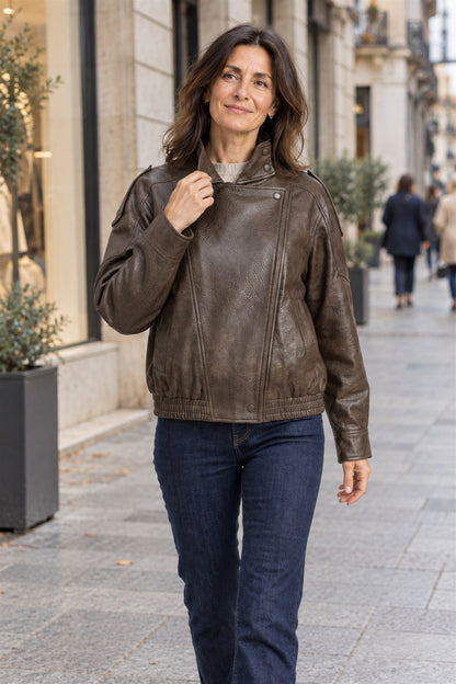 Clara en marrón con vaqueros, andando por una calle de escaparates en otoño