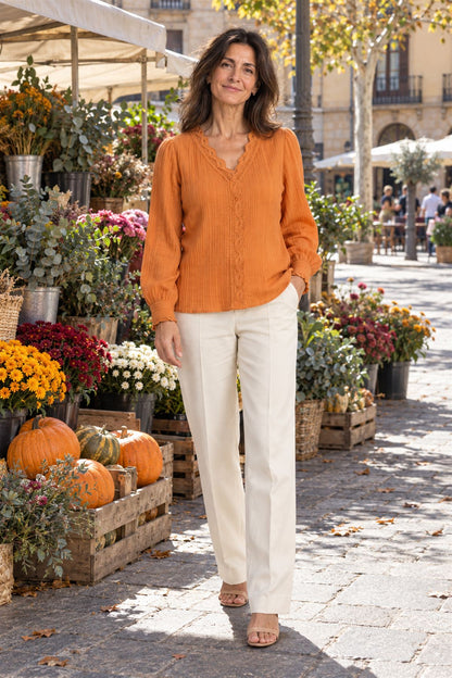 Paloma en naranja con pantalón crudo, junto a un puesto de flores y calabazas
