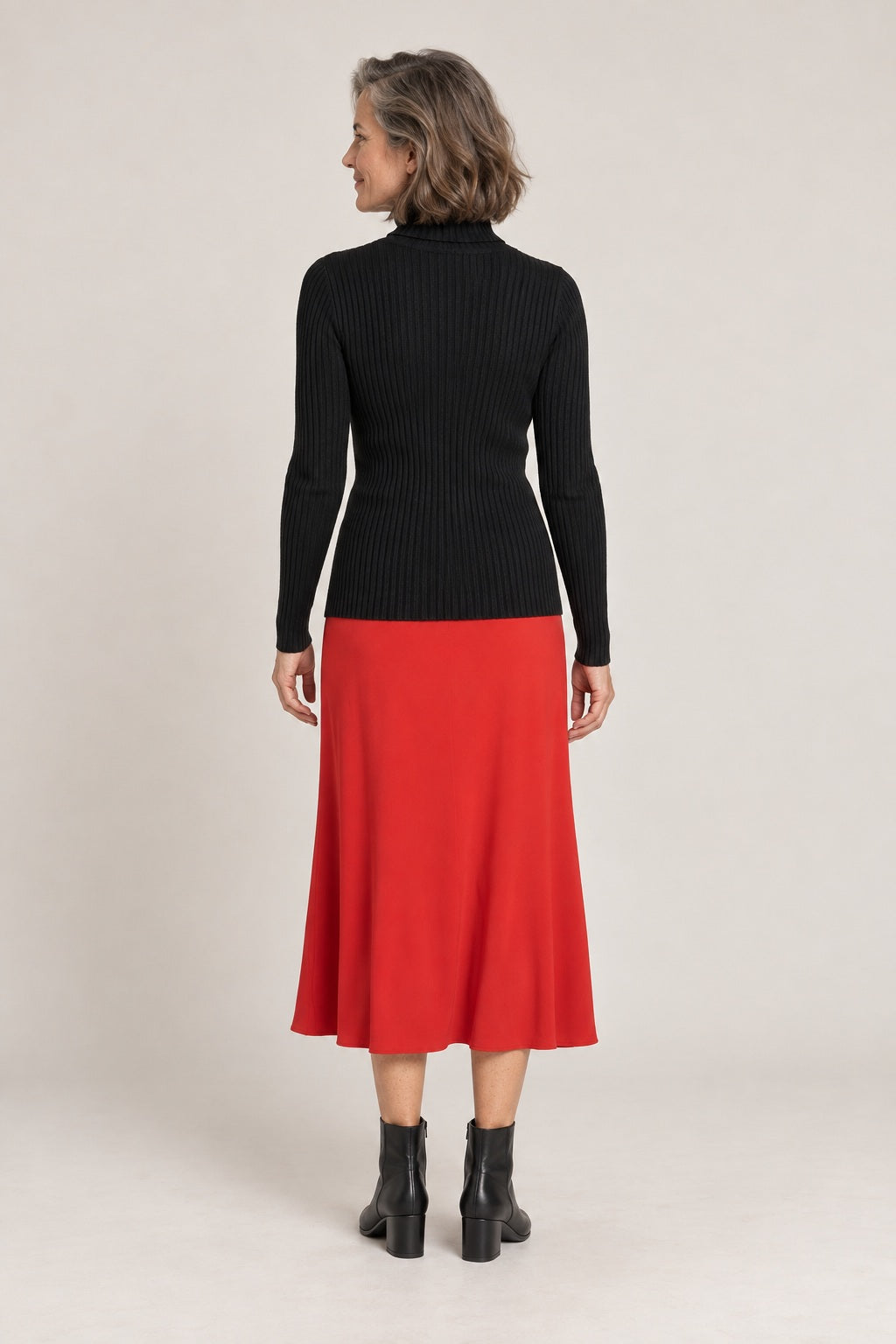 Jersey de cuello alto negro, foto de estudio de espaldas con falda roja