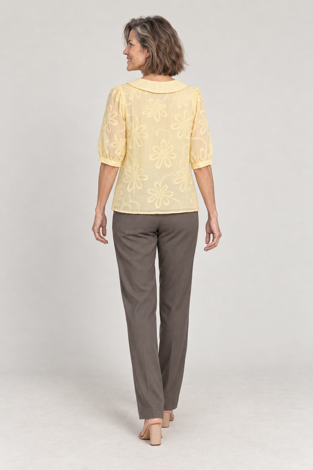 Rosalía en amarillo pálido, foto de estudio de espaldas con el cuello bebé y las flores en relieve